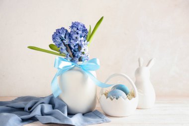 Güzel sümbül çiçekli vazo, bej duvarın yanındaki masada paskalya yumurtası ve tavşan.