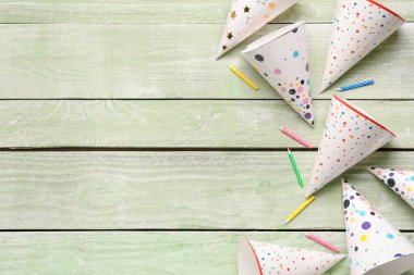 Parti şapkaları ve renkli ahşap arka planda doğum günü mumlarıyla kompozisyon