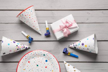 Parti şapkası, tabak, düdük ve hafif ahşap arka planda hediye kutusu olan kompozisyon, yakın plan.