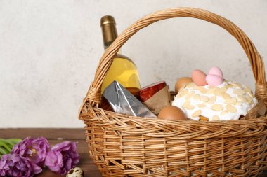 Paskalya yumurtaları, pasta ve şarap dolu sepet gri arka planda.