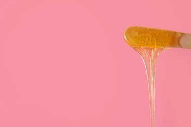 Pembe arka planda şekerleme macunu olan Spatula, yakın plan.