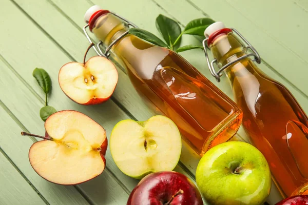 Glasflaschen Mit Frischem Apfelessig Und Früchten Auf Grünem Holzgrund — Stockfoto