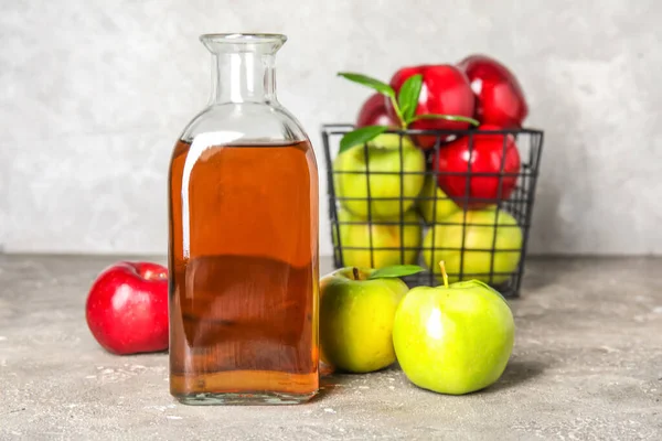 玻璃瓶的新鲜苹果醋和水果放在灰色的烤桌上 — 图库照片