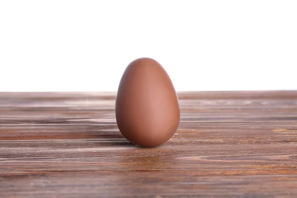 stock image Chocolate Easter egg on wooden table against white background