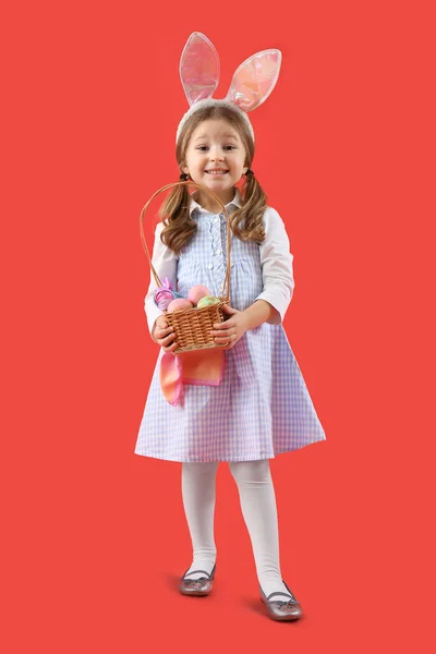 红底复活节彩蛋篮子里的兔子耳朵里可爱的小女孩 — 图库照片