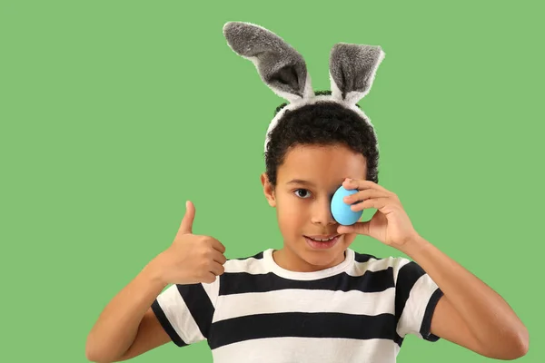 アフリカ系アメリカ人の男の子でウサギの耳でイースターエッグショー親指アップ上の緑の背景 — ストック写真