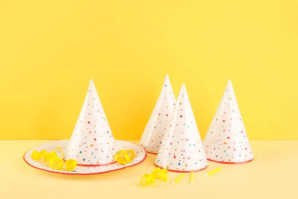 Party Hats Plate Candles Serpentine Table Yellow Wall — Stock Photo, Image