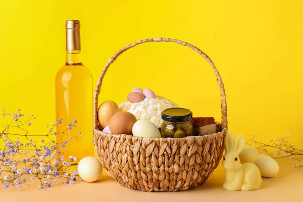 Καλάθι Πασχαλινά Αυγά Κέικ Και Μπουκάλι Κρασί Μπεζ Τραπέζι Κίτρινο — Φωτογραφία Αρχείου