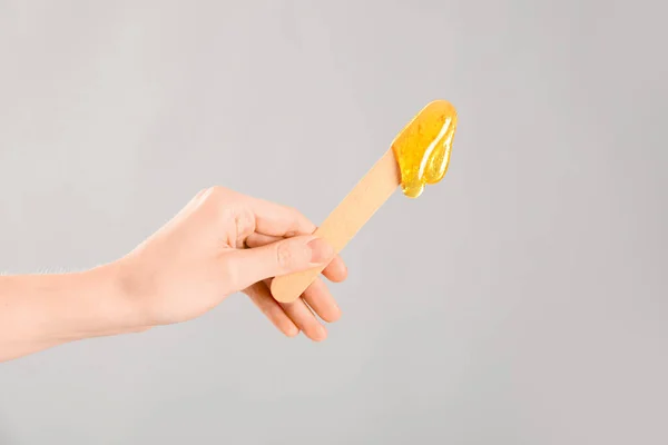 stock image Female hand holding spatula with sugaring paste on light background