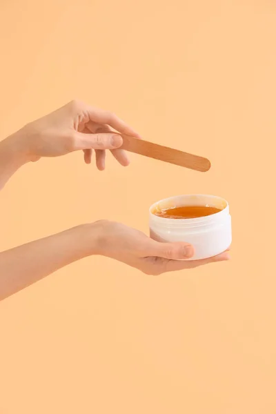 Female hands holding sugaring paste on beige background