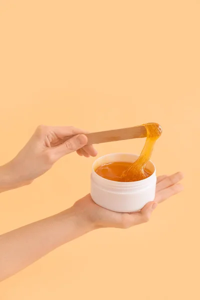 Female hands holding sugaring paste on beige background