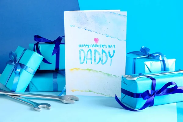 Greeting card for Father\'s Day, gifts and wrenches on color background