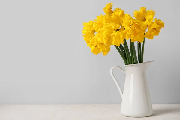 stock image Vase with narcissus flowers on table near grey wall