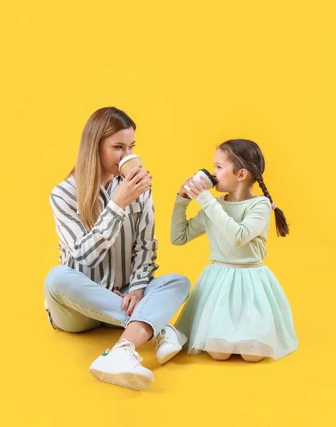 stock image Cute little girl with her mother drinking coffee on yellow background