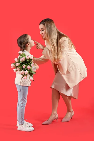 Mother Touching Her Little Daughter Nose Tulips Red Background — Stock Photo, Image