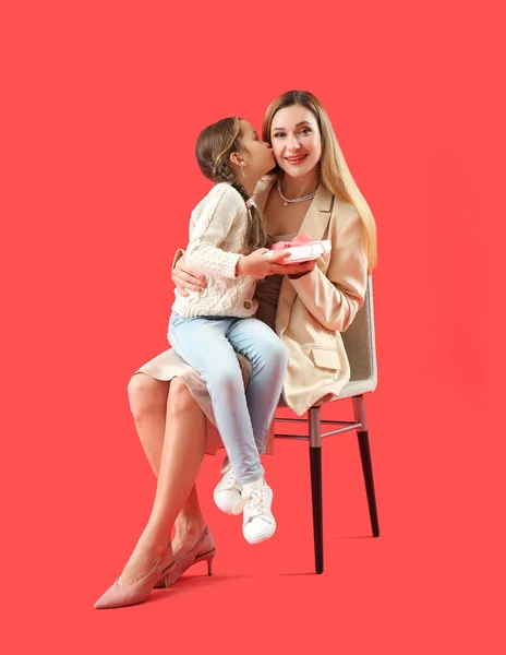 Schattig Klein Meisje Met Haar Moeder Cadeau Zitten Rode Achtergrond — Stockfoto
