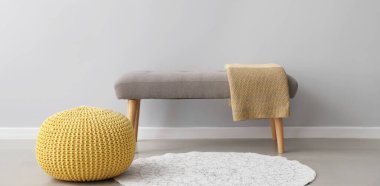 Odadaki ışık duvarının yanında ekose kumaşlı rahat puf ve bank.