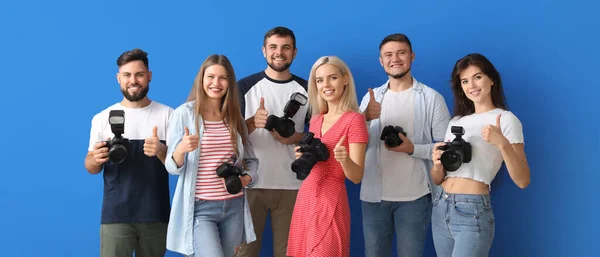 一群快乐的年轻摄影师在蓝色的背景上摆出大拇指的姿势 — 图库照片