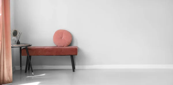 Pink bench with cushion and table in light room. Banner for design