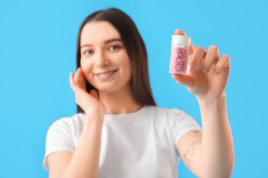 Mavi arka planda vitamin takviyesi olan genç bir kadın. Yakın plan.