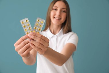 Mavi arka planda vitamin takviyeleri olan güzel bir kadın.