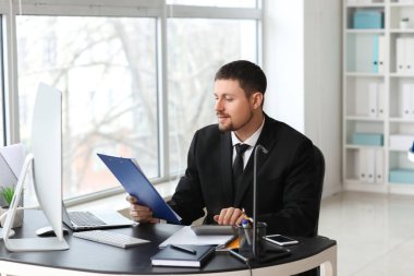 Ofisteki masada evrak ve hesap makinesiyle çalışan erkek muhasebeci