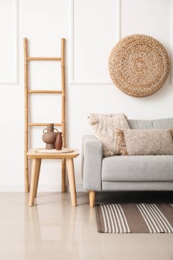 Gri kanepesi, masası ve merdiveniyle aydınlık oturma odasının içinde.