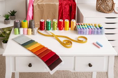 İp makaraları, kumaş örnekleri ve atölyedeki şeritlerle terzinin işyeri