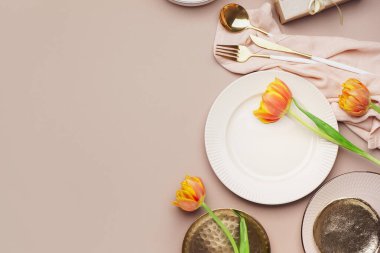 Temiz plakalı kompozisyon, lale çiçekleri ve bej arka planda çatal bıçak takımı.