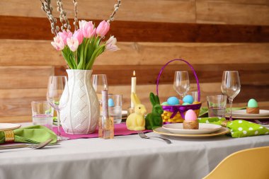 Beautiful Easter table setting with flowers and eggs in dining room clipart