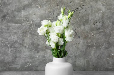 Grunge arka planında beyaz Eustoma çiçekleri olan vazo