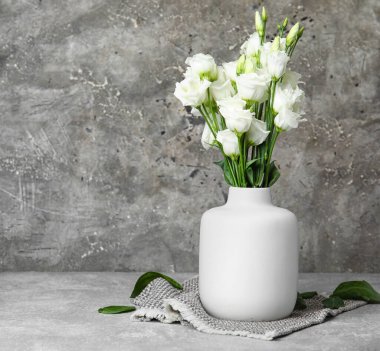 Grunge arka planında beyaz Eustoma çiçekleri olan vazo