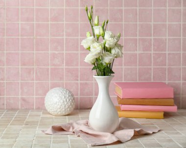 Çok güzel Eustoma çiçekleri, kitapları ve renk arkaplanı dekoru olan vazo.