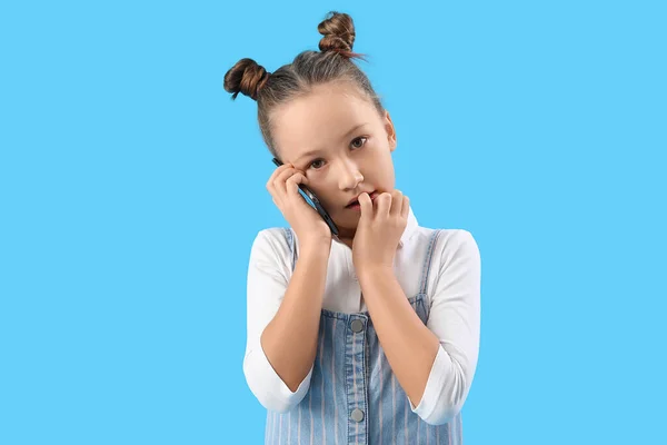 Little Girl Biting Nails While Talking Mobile Phone Blue Background — Zdjęcie stockowe