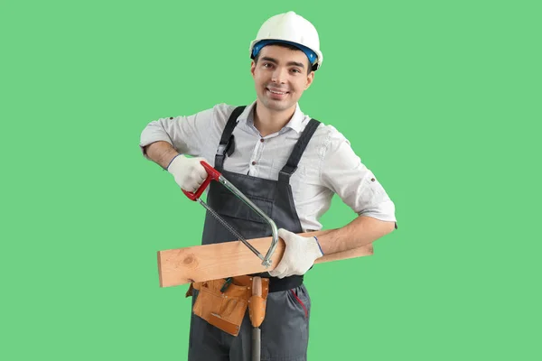 Young Carpenter Hacksaw Wooden Plank Green Background — Stock Photo, Image