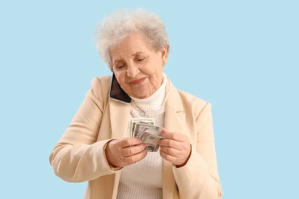 Mulher Sênior Com Dinheiro Falando Por Telefone Celular Fundo Azul — Fotografia de Stock