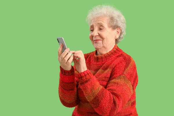 Starsza Kobieta Korzystająca Telefonu Komórkowego Zielonym Tle — Zdjęcie stockowe
