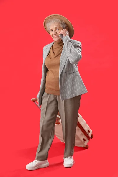 Idős Bőrönddel Beszél Mobiltelefonnal Piros Alapon — Stock Fotó