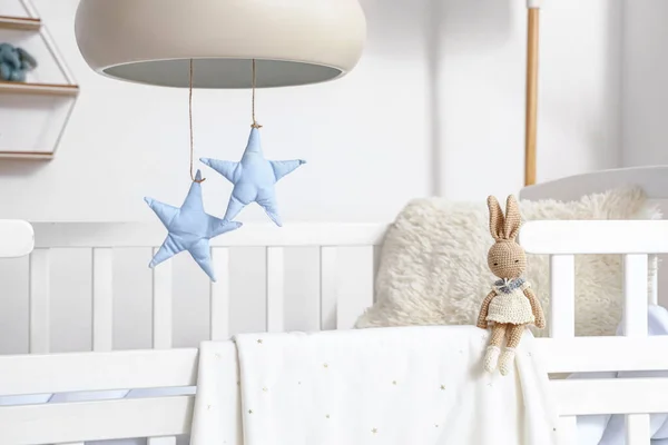 Baby crib with toy bunny in bedroom, closeup