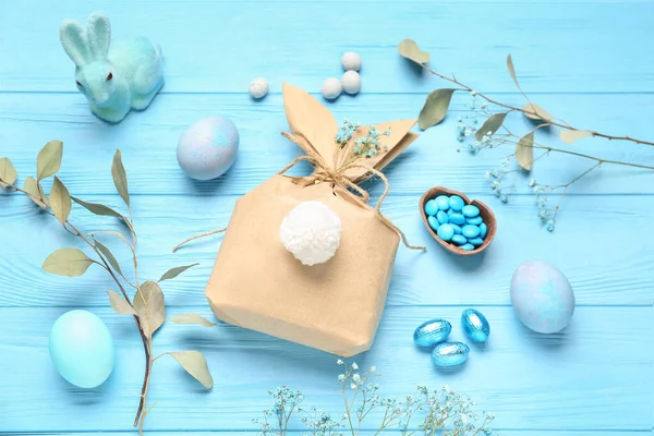配上兔子礼品袋 复活节彩蛋及蓝色木制背景花卉装饰 — 图库照片