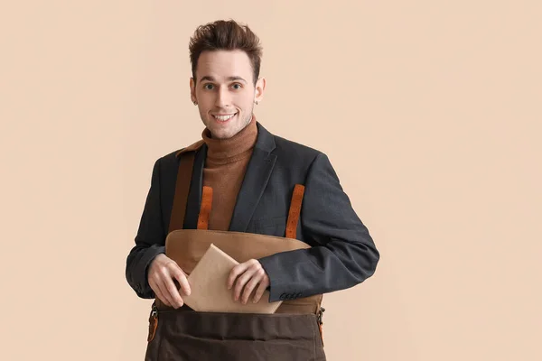 Young Man Putting Book Bag Beige Background — Stock Photo, Image