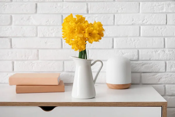 花瓶とともにナルシシズムの花や本近くの白いレンガの壁のテーブルの上 — ストック写真