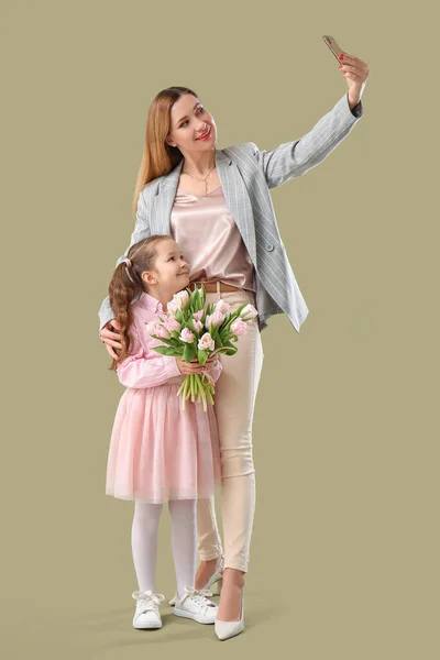 可爱的小女孩与郁金香和她的母亲采取绿色背景自拍 — 图库照片