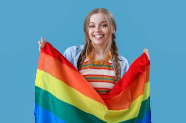 Beautiful young woman with LGBT flag on blue background