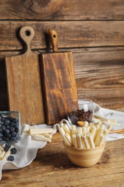 Bowl with delicious wafer rolls on wooden background