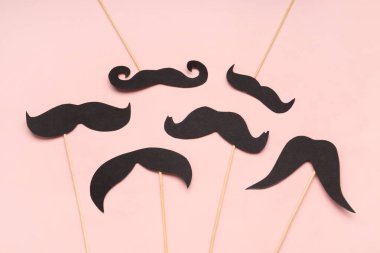 Pembe arka planda farklı kağıt bıyıklı tahta çubuklar.