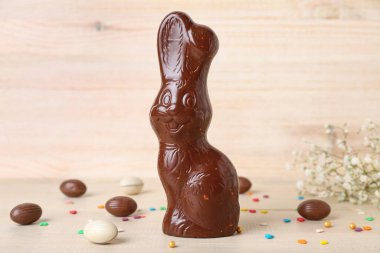 Çikolatalı Paskalya tavşanı. Yumurta ve hafif ahşap arka planda serpiştirilmiş.