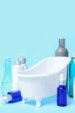 Renkli arka planda küçük küvet ve farklı kozmetik ürünleri