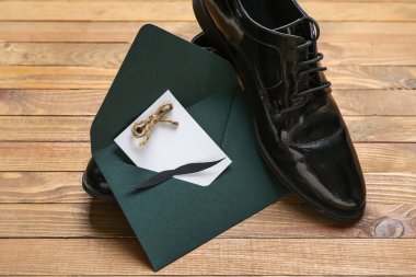 İçinde boş kart, kağıt bıyık ve tahta arka planda ayakkabılar olan bir zarf. Babalar günü kutlaması.