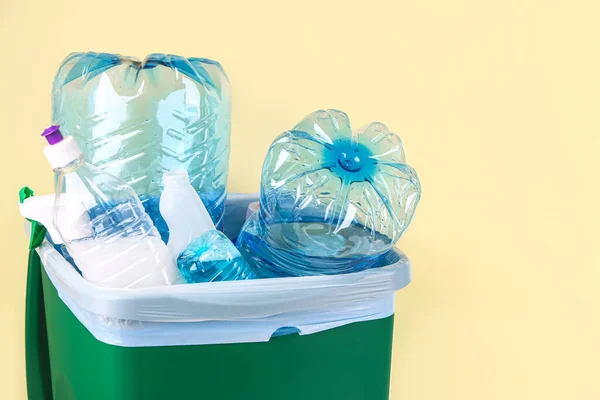 Recycle bin with plastic bottles on yellow background, closeup